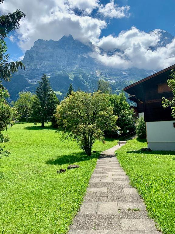a stone path in a field with a mountain in the background at Brand New, 5min to Ski PARADISE ! in Grindelwald