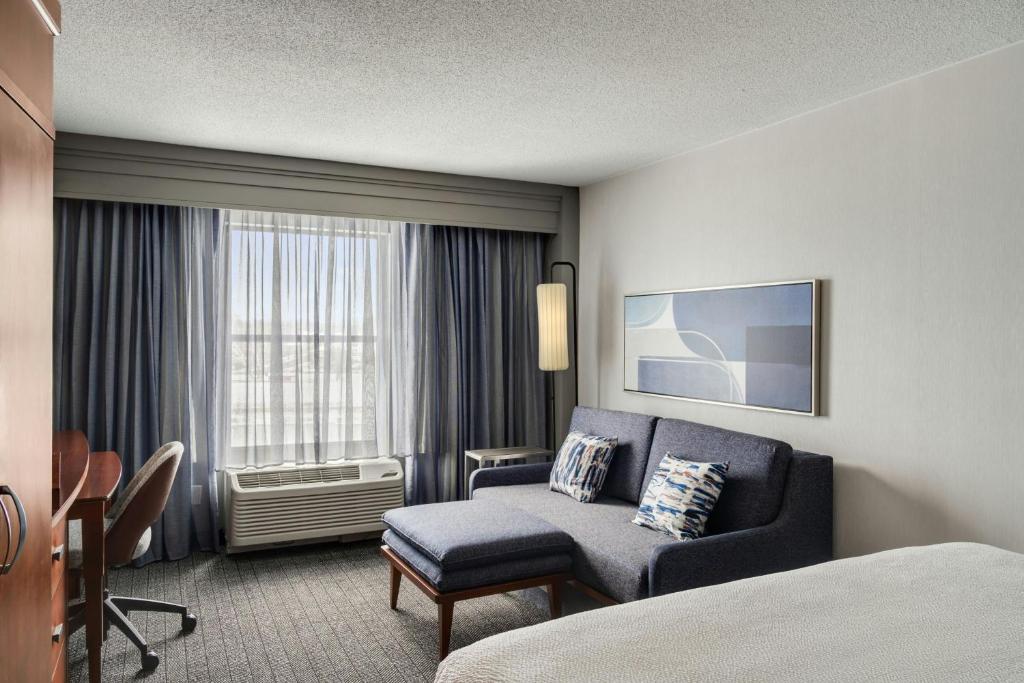 a hotel room with a bed and a couch and a window at Courtyard Hamilton in Hamilton