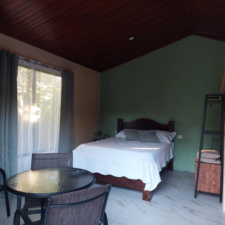 a bedroom with a bed and a table and a window at Green Trails Miravalles in Bagaces