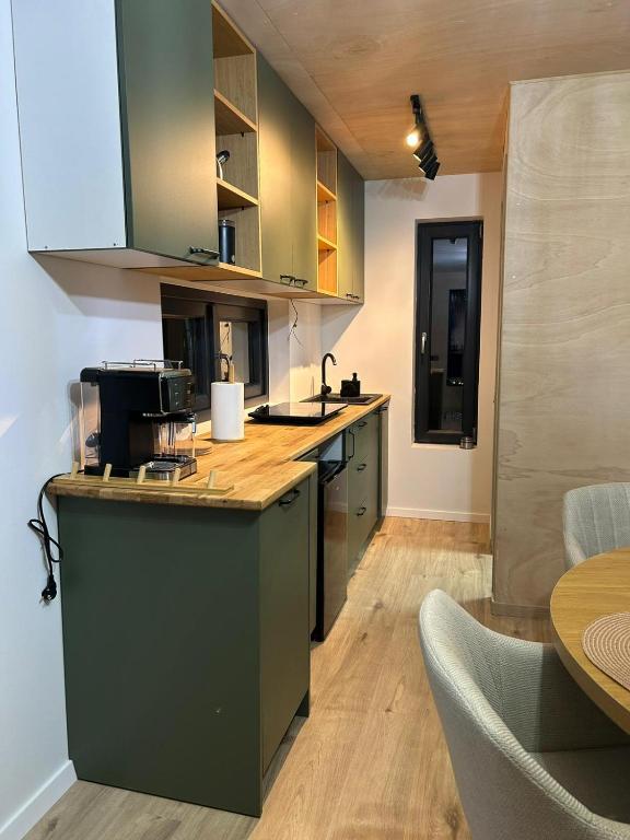 a kitchen with green cabinets and a wooden counter top at Tiny Marae in Straja