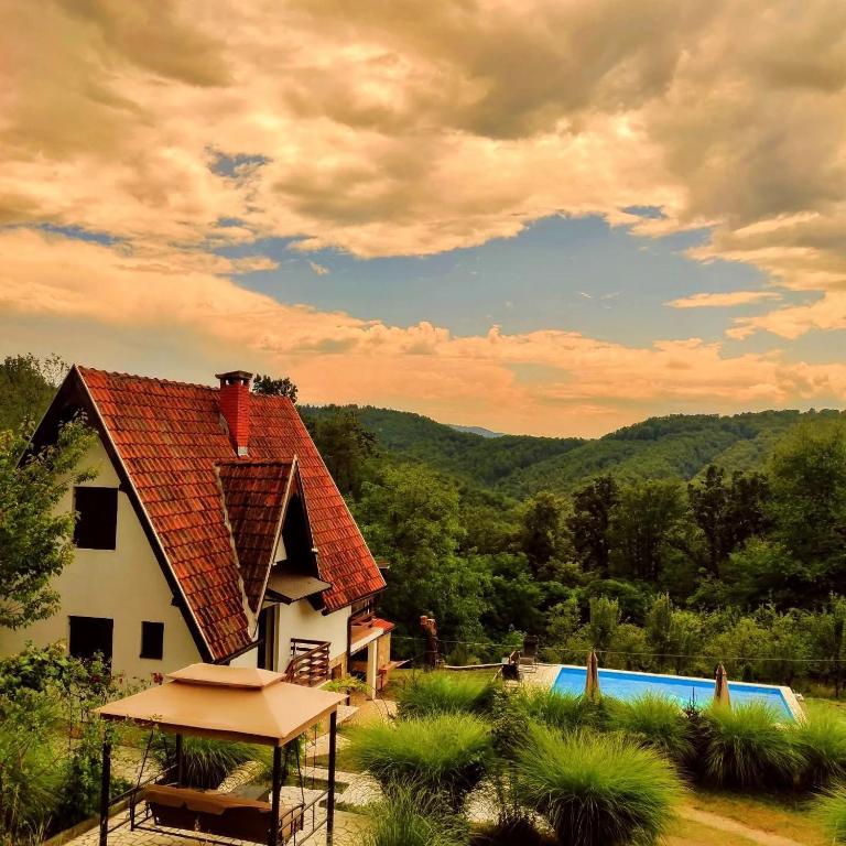 a house with a tile roof next to a swimming pool at Vikendica Popovic in Doboj