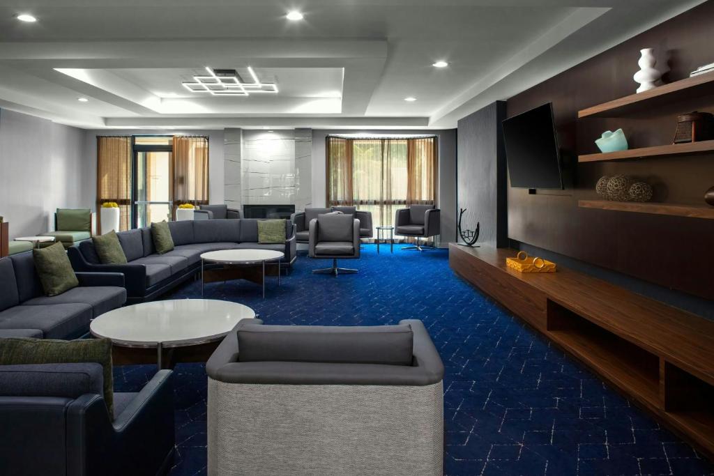 a living room with couches and a tv and tables at Courtyard by Marriott Richmond Northwest in Henrico