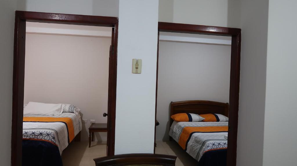 a bedroom with two beds and two mirrors at Centro Macas in Macas