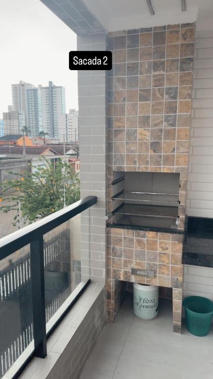 a balcony with a stone fireplace on a building at Casa 3 dormitórios 100 metros da praia in Praia Grande