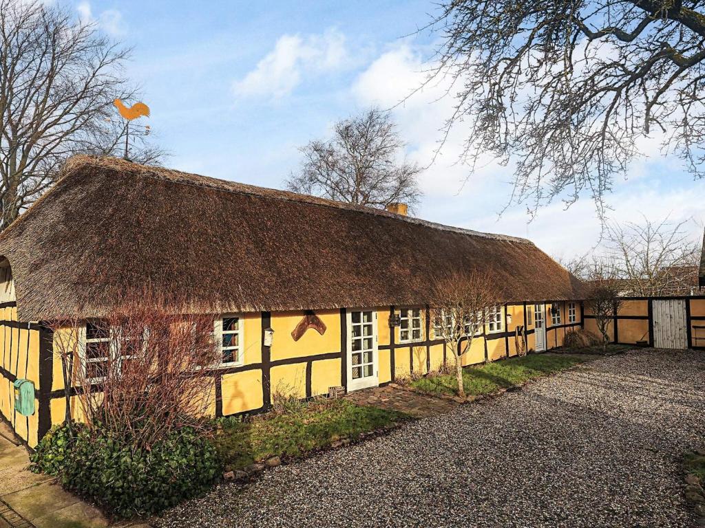 an old yellow building with a thatched roof at 4 person holiday home in Asaa in Aså
