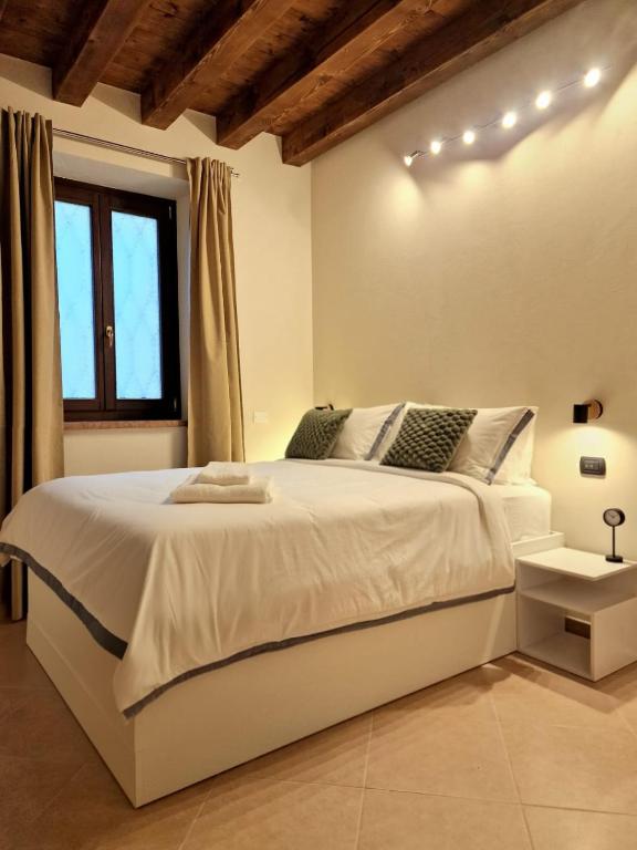 a white bedroom with a large white bed and a window at HolidHome - Soave Borgo Suite - Mini appartamento di charme nelle mura medievali in Soave