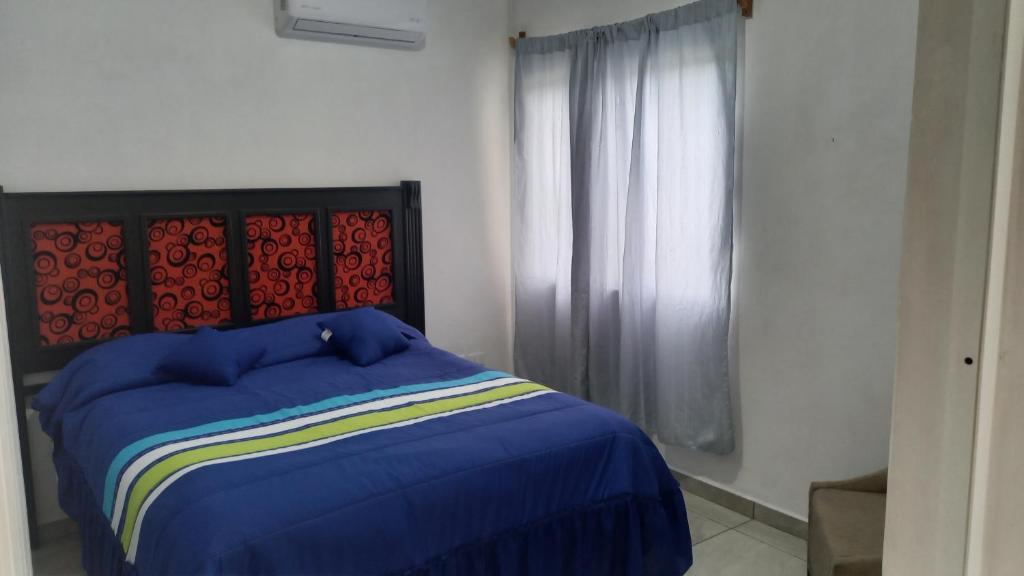 a bedroom with a blue bed and a window at Spacious house near the beach in Mazatlán