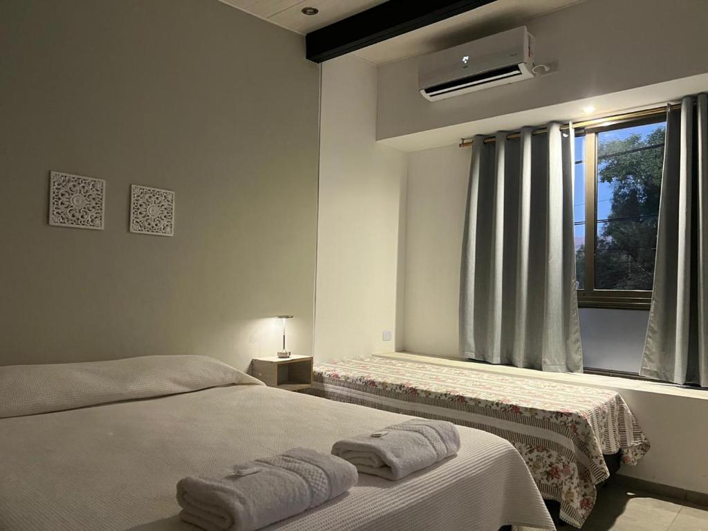a white bedroom with two beds and a window at Olmos Suites in Mina Clavero