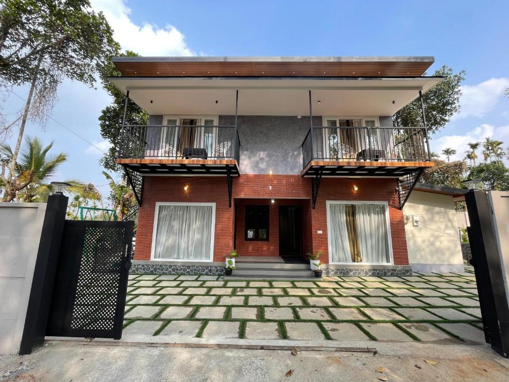 a house with a balcony and a driveway at Nellarachal Homestay in Ambalavayal