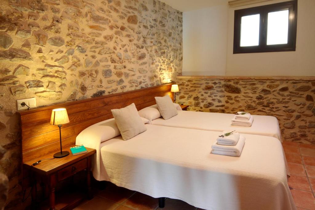 duas camas num quarto com uma parede de pedra em Vilars 10 em Espolla
