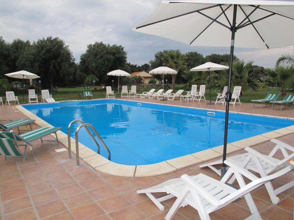 a large swimming pool with chairs and an umbrella at Stella Di Sicilia in San Fratello