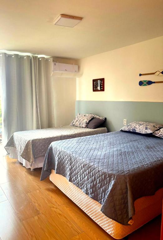 a bedroom with two beds and a window at Suíte aMAR in São Pedro da Aldeia