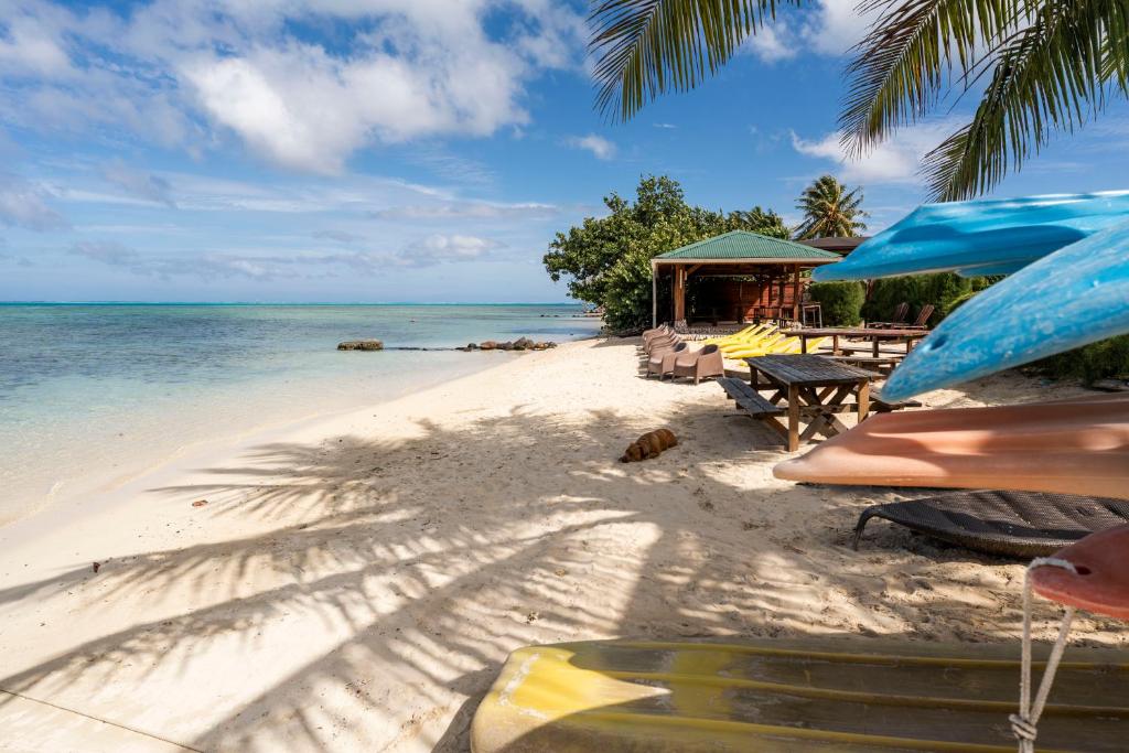 a beach with chairs and tables and the ocean at Moorea Maatea Tahatai Lodge in Moorea