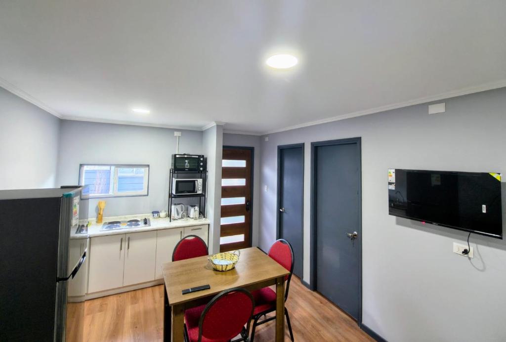 a kitchen and dining room with a table and red chairs at Arriendo en Valdivia cabañas in Valdivia