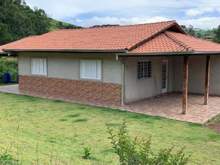 a brick house with a red roof and a yard at Sítio Canario da Terra in Gonçalves