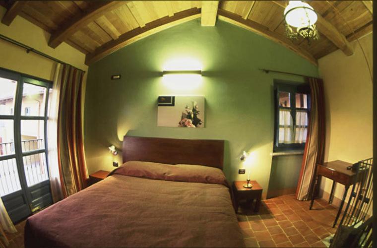 Cisterna dʼAstiにあるAlbergo Ristorante Garibaldiの緑の壁のベッドルーム1室(大型ベッド1台付)