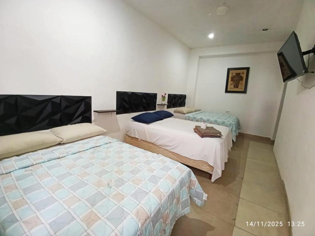 a bedroom with two beds and a flat screen tv at Hotel y Hostal AH MUN in Mérida