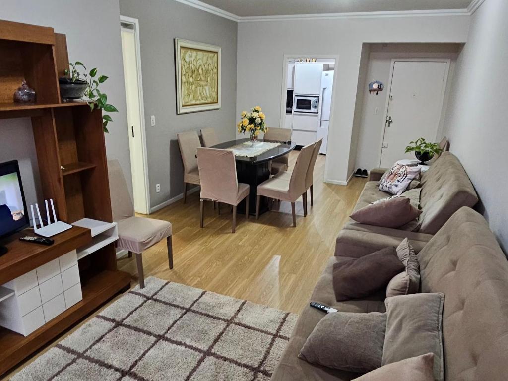 a living room with a couch and a dining room at Apartamento Beira-mar praia centro itapema in Itapema