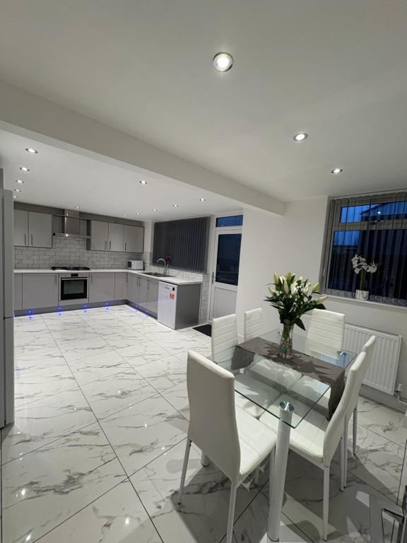 a kitchen with a glass table and white chairs at Luxury modern guest house in Birmingham
