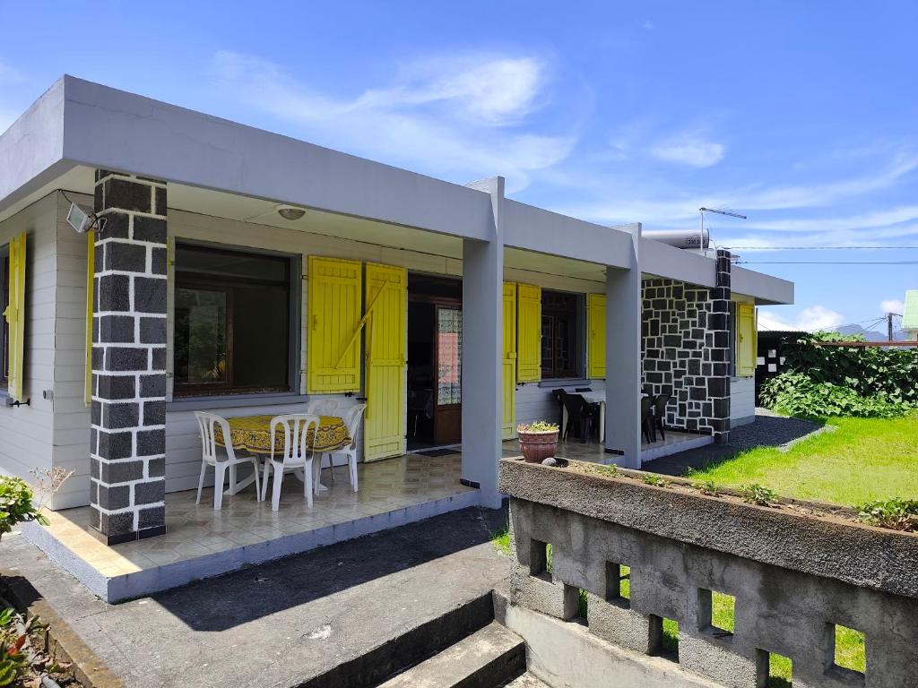 a yellow house with a table and chairs at La villa Madelon in Cilaos