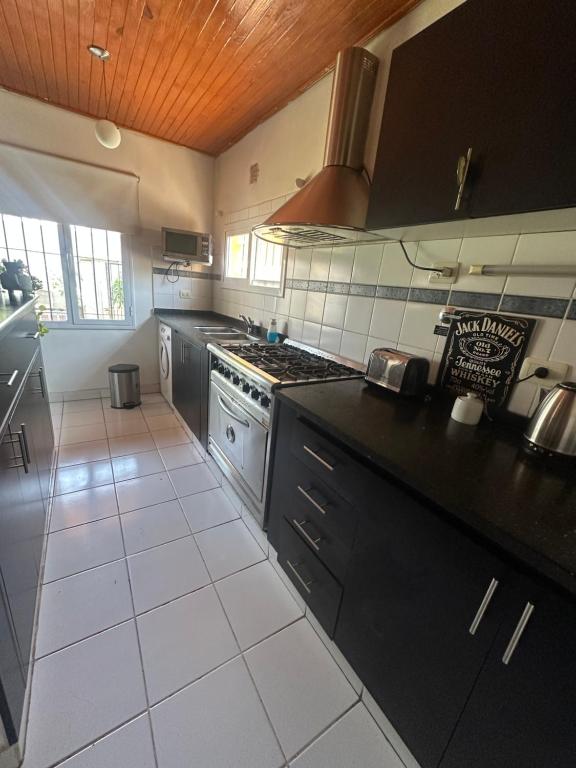 a kitchen with black cabinets and a white tile floor at Alquiler temporal in Plottier
