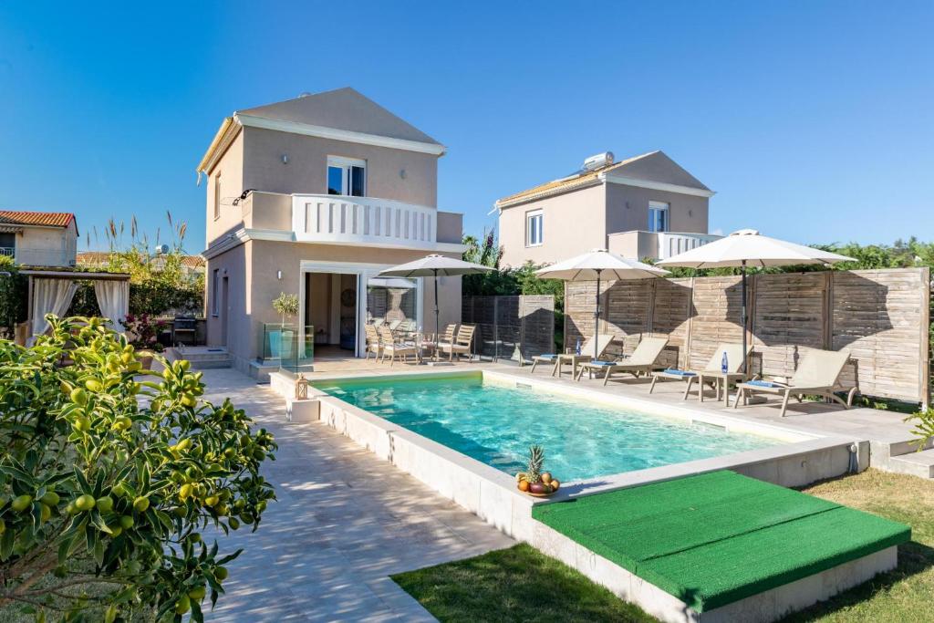 a villa with a swimming pool in front of a house at Erato by Vintage Travel in Tsoukalades