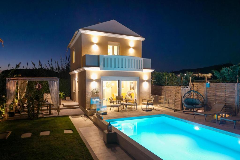 a villa with a swimming pool in front of a house at Klio by Vintage Travel in Agios Georgios
