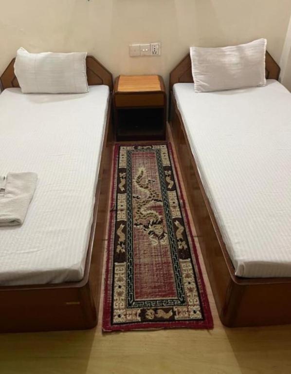 two twin beds in a room with a rug at Bhuddha Bhoomi Lodge in Rummindei