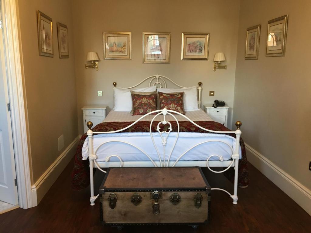 a bedroom with a white bed with a trunk in it at Balham Lodge in London