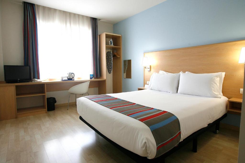 a hotel room with a large bed and a desk at Travelodge Torrelaguna in Madrid