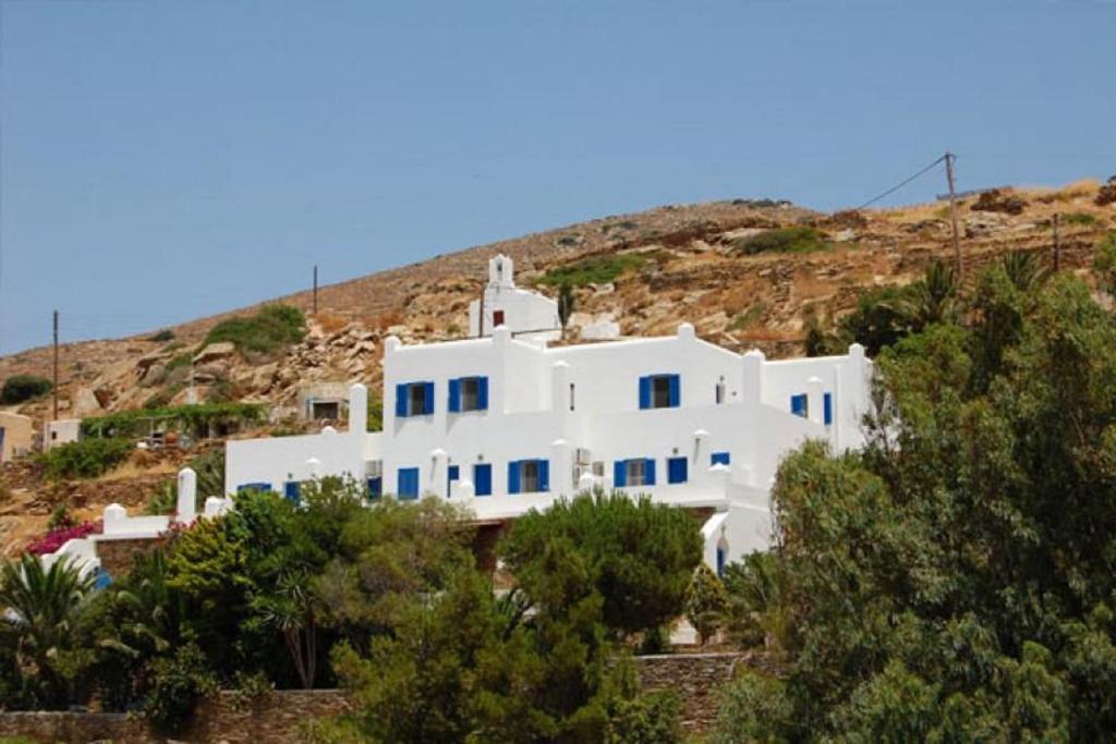 una casa blanca en la cima de una colina con árboles en Country House Apartments, en Ios Chora