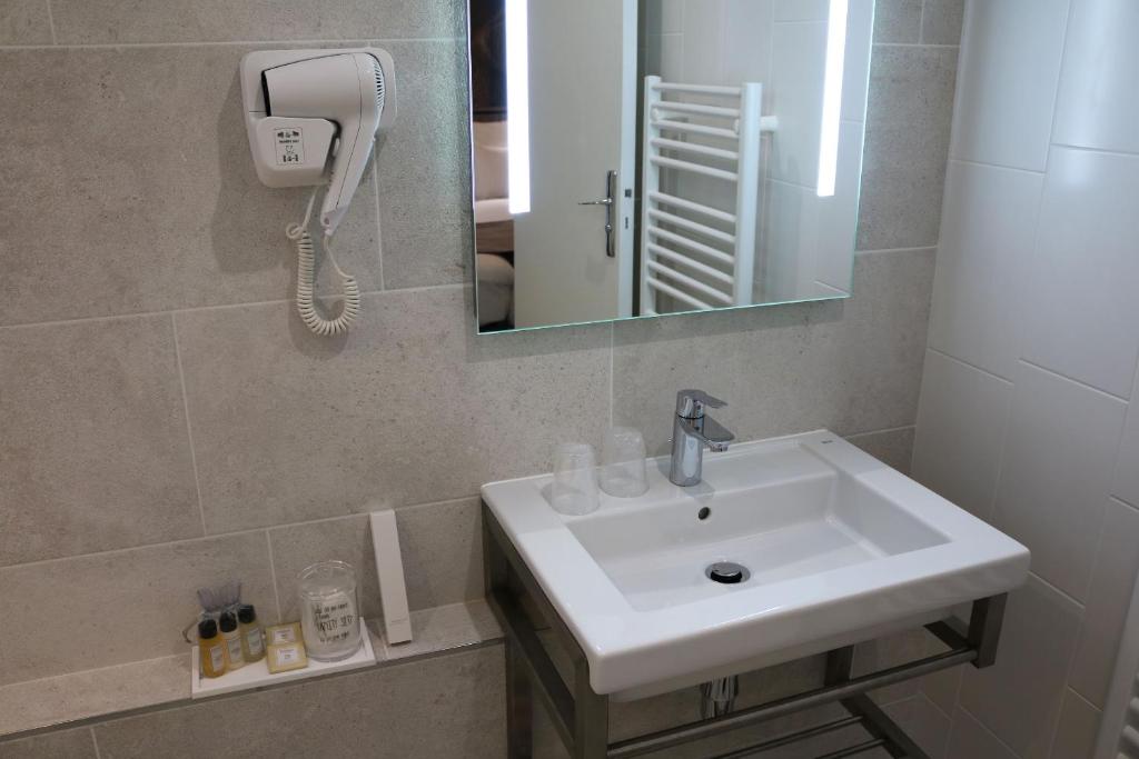 a white sink sitting under a mirror in a bathroom at Le Saint Aubert in Le Mont Saint Michel