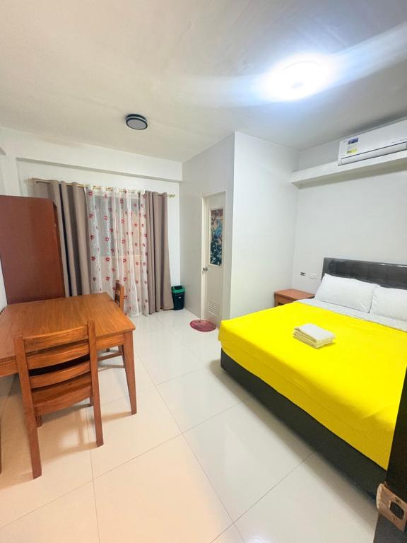 a bedroom with a yellow bed and a wooden table at Guest hotel Palestina Pili in Pili