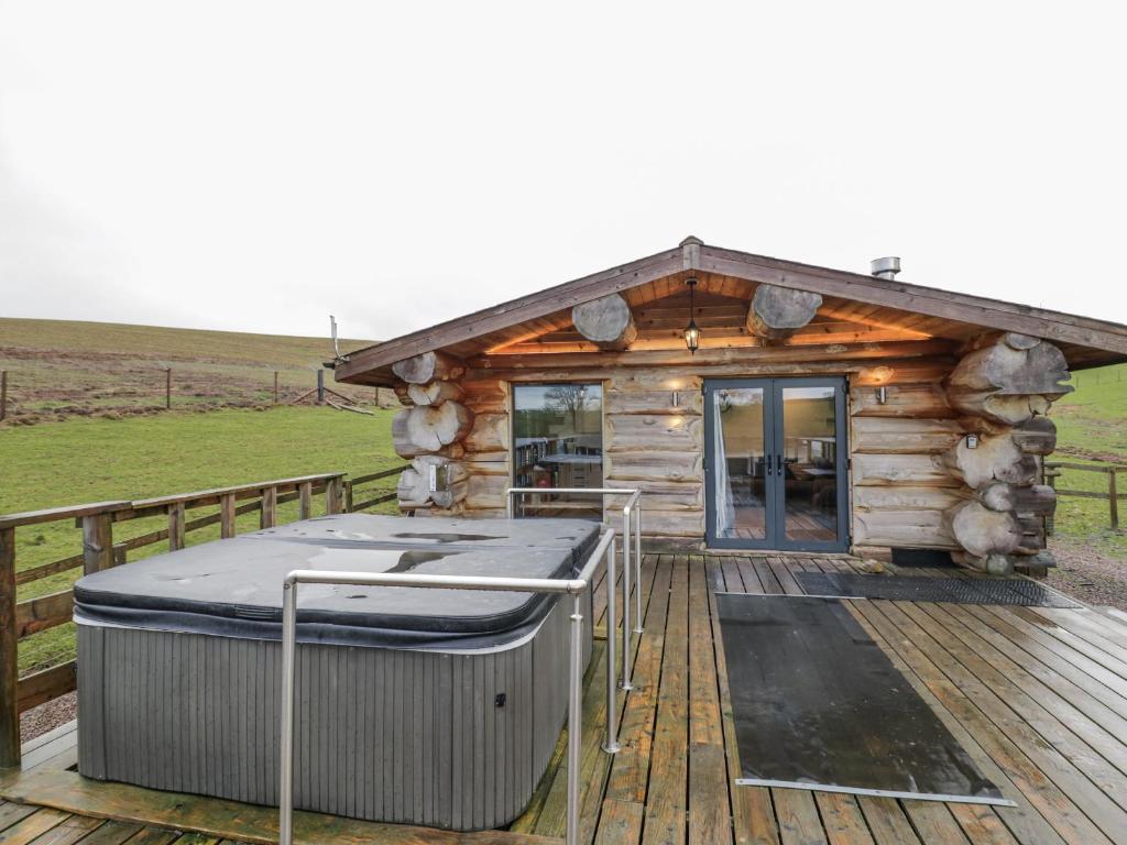 a log cabin with a hot tub on a deck at Douglas Cabin at Salford Court Farm Fishing Cabins in Worcester