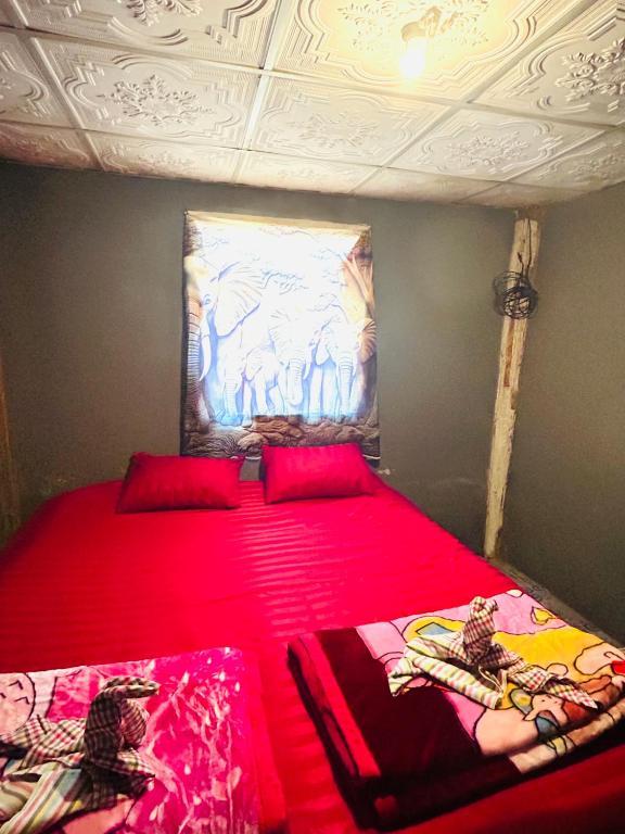 a bedroom with two beds with red sheets and a painting at Whatsup pai in Pai