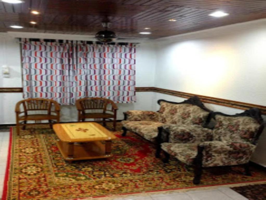 ein Wohnzimmer mit einem Sofa, 2 Stühlen und einem Tisch in der Unterkunft Nur Muslim 2 Homestay At Kota Bharu in Kota Bharu