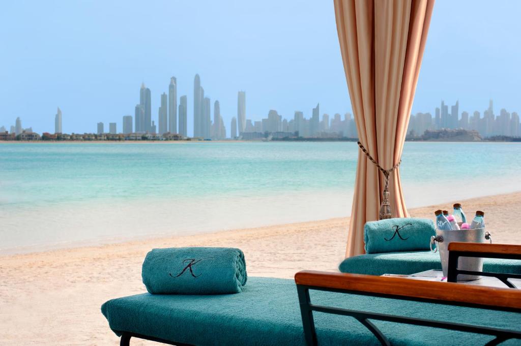a beach with two lounge chairs and the ocean at Kempinski Hotel Palm Jumeirah in Dubai