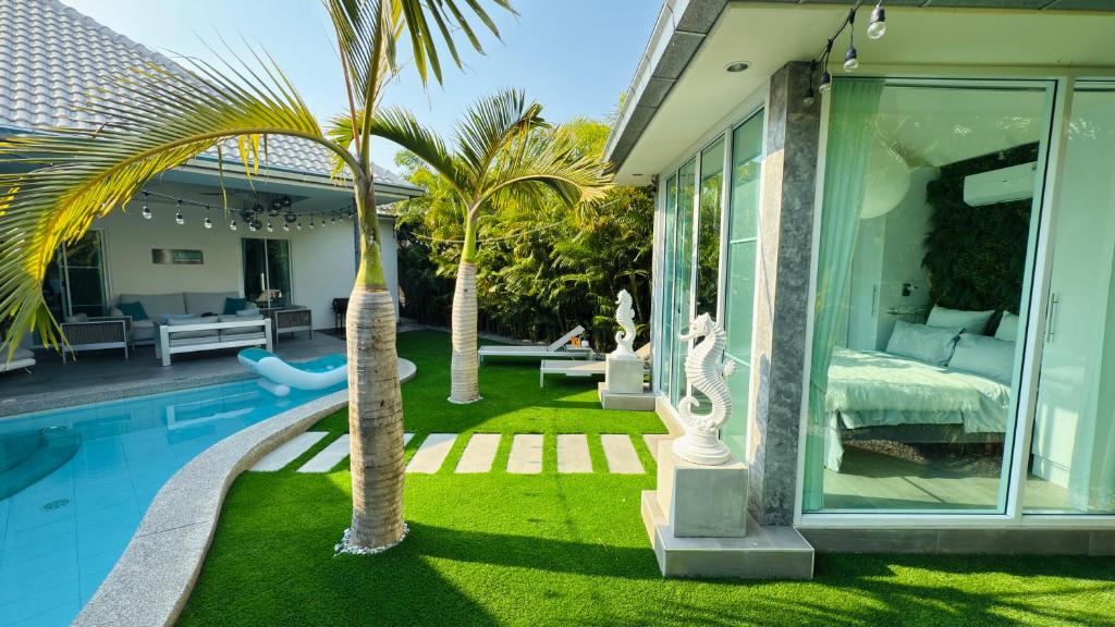 a house with a swimming pool with palm trees in the yard at Lagoon Poolvillas Pattaya in Ban Huai Yai