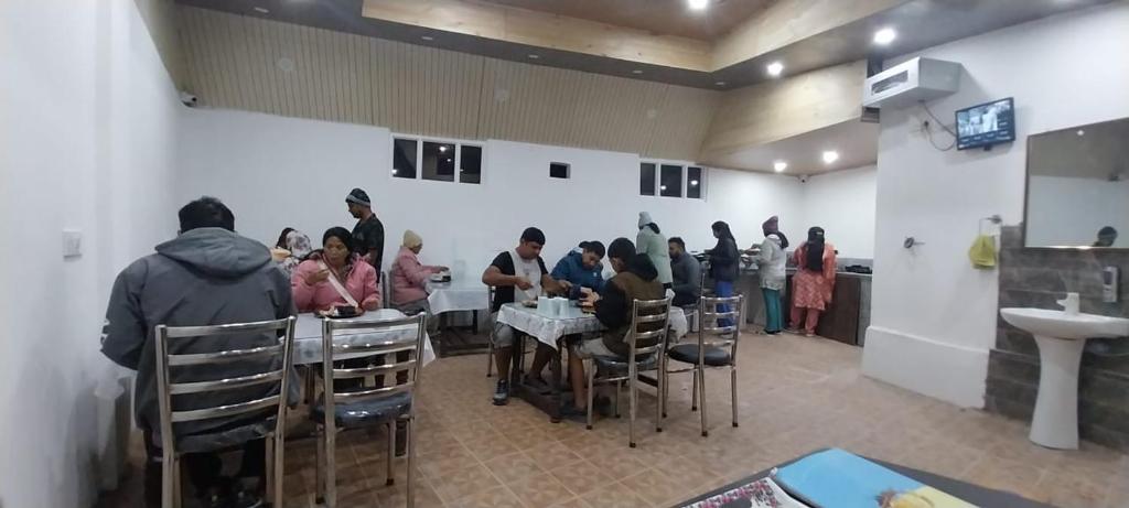 a group of people sitting at tables in a room at Green Resort in Rājbāgh