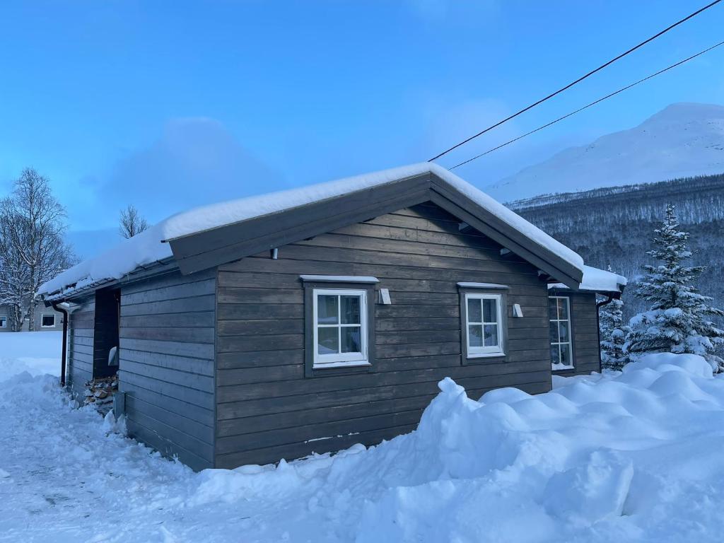a small wooden cabin with snow around it at Lyngen Alps Cabin with Sauna, Northern Lights & Ski Touring, 1h from Tromsø in Indre Tomasjord