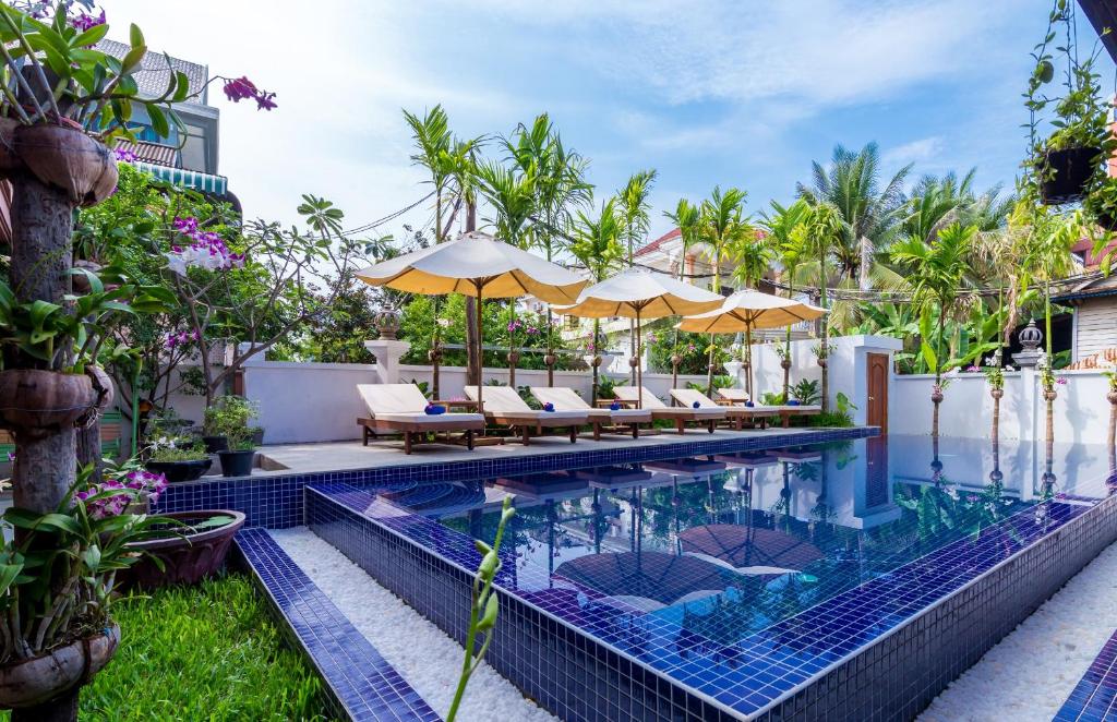 einen Infinity-Pool mit Stühlen und Sonnenschirmen in einem Resort in der Unterkunft The Unique Angkor Villa in Siem Reap