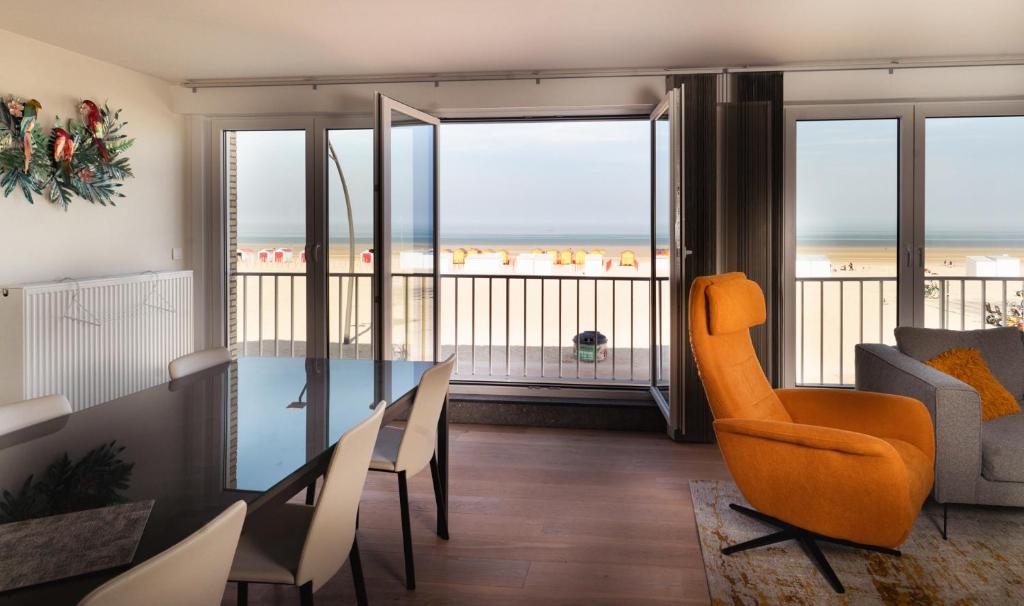 a living room with a dining table and a view of the ocean at Appartement de Panne zeedijk in De Panne