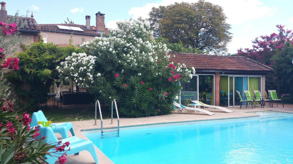 a swimming pool in a yard with chairs and flowers at La Villa des Violettes in Toulouse