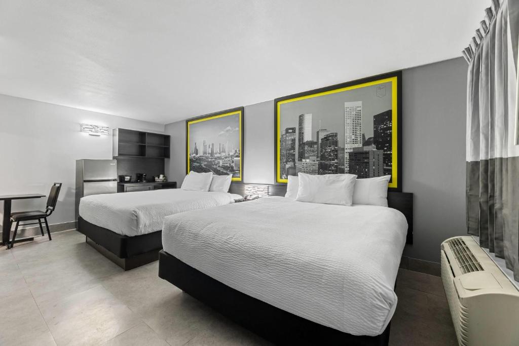 a hotel room with two beds and a desk at Super 8 by Wyndham Texas City - Galveston Area in Texas City