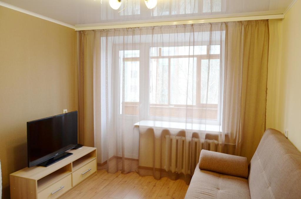 a living room with a television and a window at "GOOD NIGHT" on Pirogova 7 in Tomsk