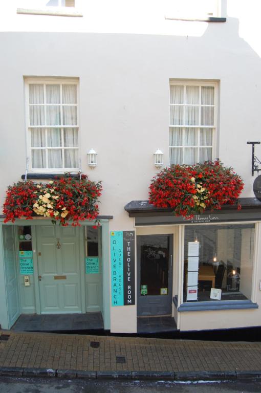 een wit gebouw met twee ramen en bloemen op de deuren bij The Olive Branch in Ilfracombe