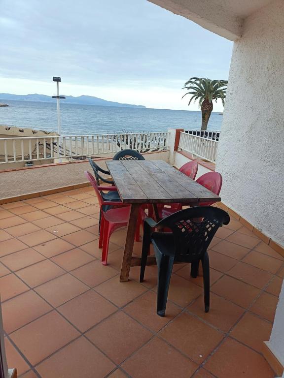 a wooden table and chairs on a patio overlooking the ocean at Frente Mar in L'Escala