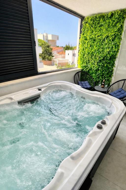 a hot tub in a room with a large window at Holiday House Maze with jacuzzi in Novalja