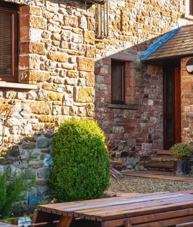 a brick building with a bench in front of it at Old Well Cottage Barn Conversion in Penrith