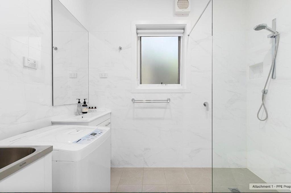 a white bathroom with a shower and a sink at Cromwell Lite in Cooma